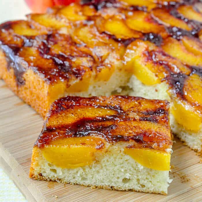 Peach Upside Down Cake close up photo of a single sice on a wooden cutting board.