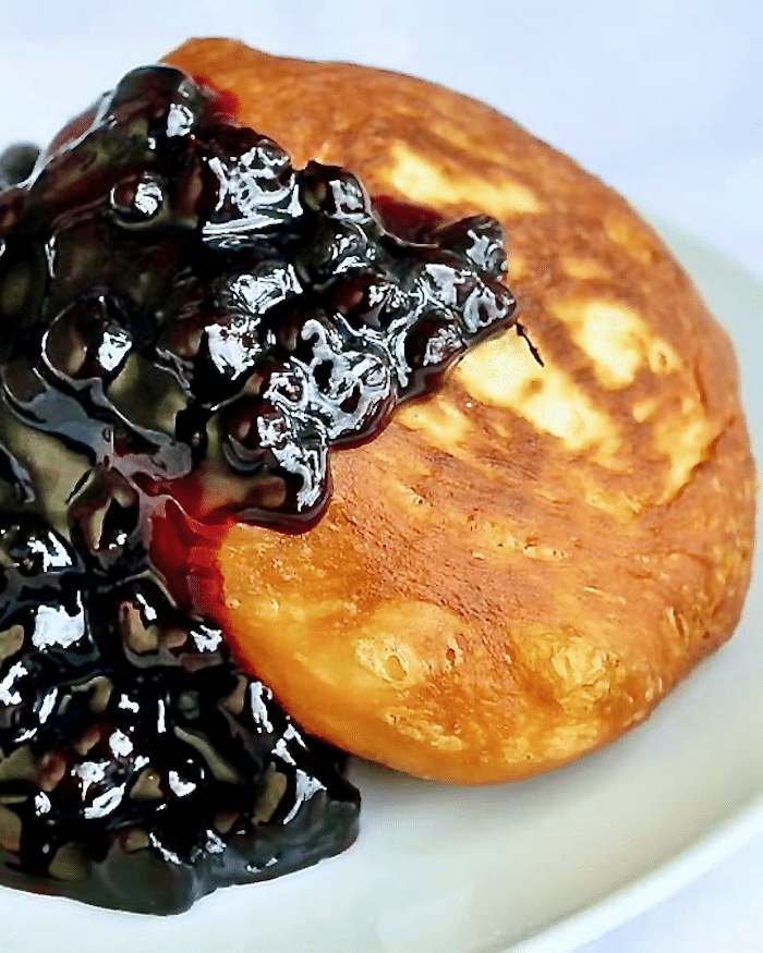 Brioche Toutons with Blueberry Honey Sauce close up photo of one serving on a white plate.