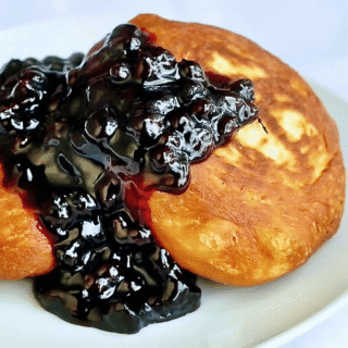 Brioche Toutons with Blueberry Honey Sauce photo of one serving on a white plate.