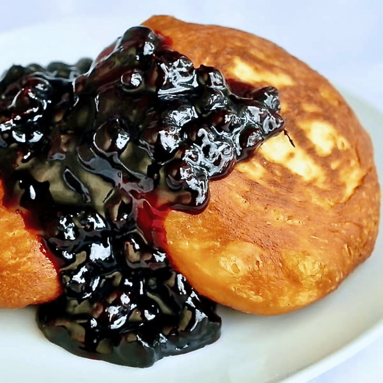 Brioche Toutons with Blueberry Honey Sauce photo of one serving on a white plate.