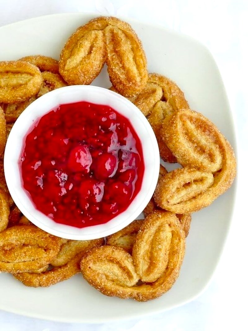 Close up photo of Cinnamon Palmiers with Raspberry Compote shown on a square white plate photographed from overhead.
