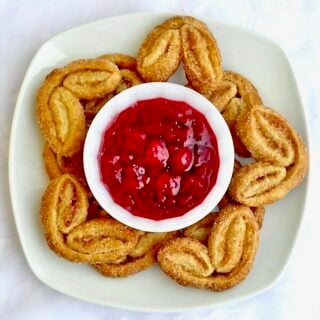 Cinnamon Palmiers with Raspberry Compote shown on a square white plate photographed from overhead.
