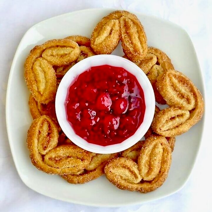 Cinnamon Palmiers with Raspberry Compote shown on a square white plate photographed from overhead.
