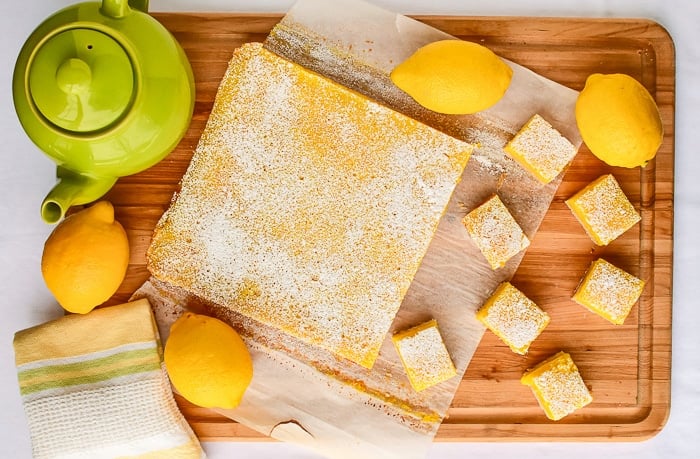 Overhead photo of lemon bars being cut on a wooden board