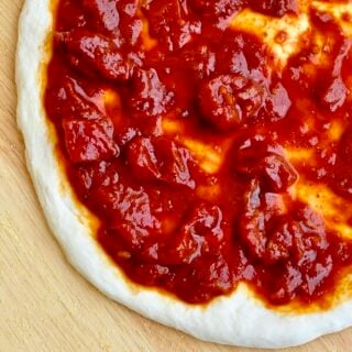 Perfect Pizza Sauce photo of sauce in stretched pizza dough square cropped photo for Google featured image.