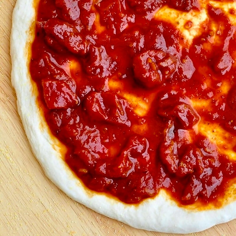 Perfect Pizza Sauce photo of sauce in stretched pizza dough square cropped photo for Google featured image.