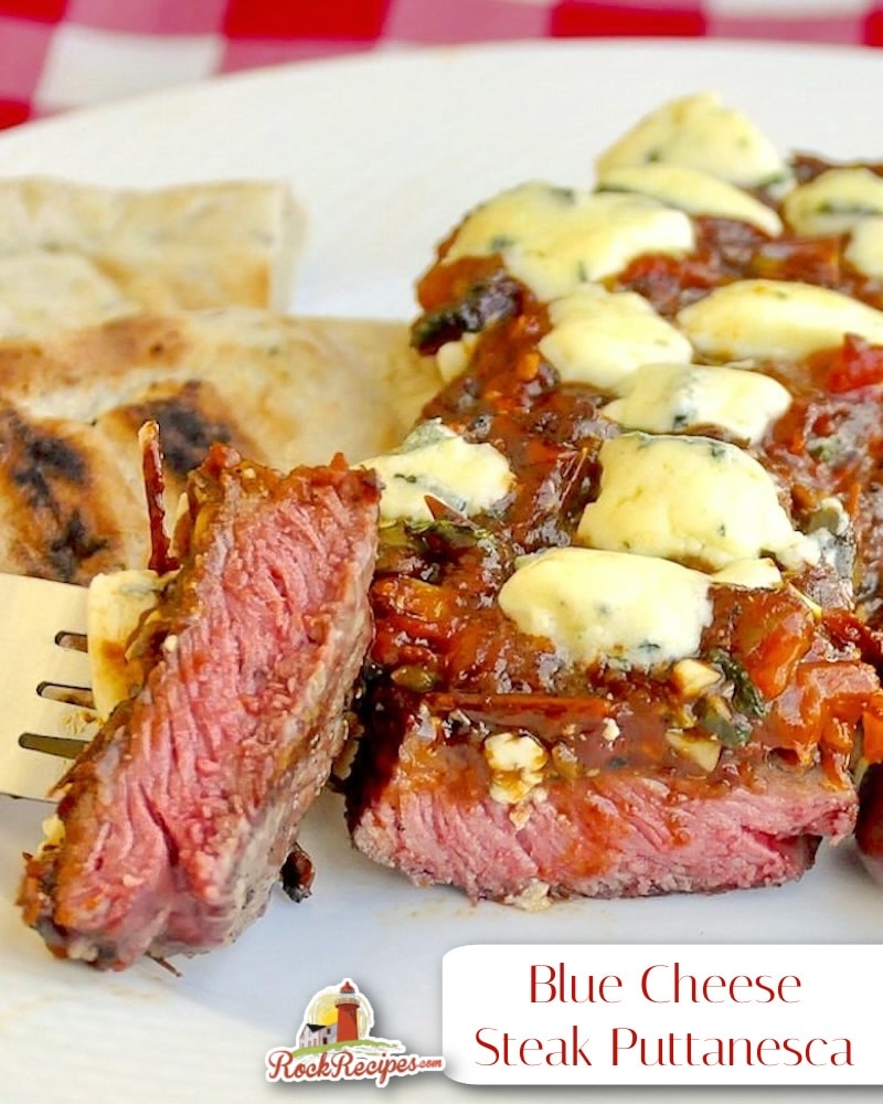 Blue Cheese Steak Puttanesca close up of a sliced bite of steak on a fork with title text added for social media posts.