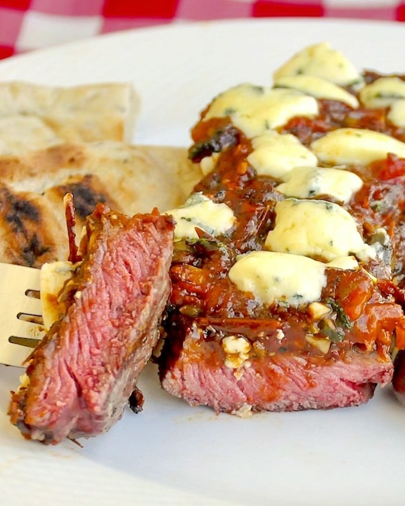 Blue Cheese Steak Puttanesca close up of a sliced bite of steak on a fork