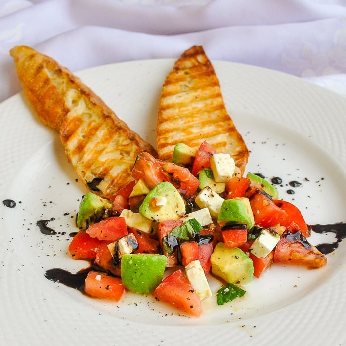 Tomaten-Avocado-Feta-Crostini als Einzelportion auf weißem Teller