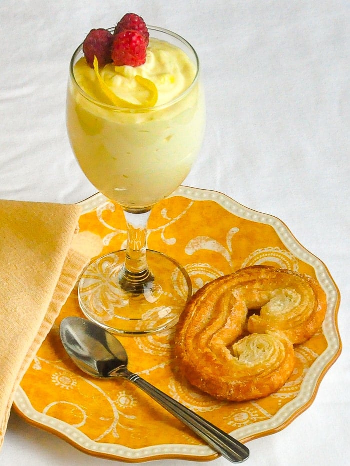 Easy Lemon Mousse in a wine glass on a yellow patterned plate.