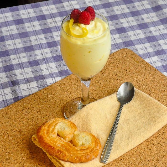 Easy Lemon Mousse in a wine glass with a palmier cookie, napkin and spoon at the base
