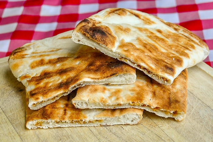 Coconut Cashew Raisin Naan wide shot photo of cooked naans on a wooden cutting board