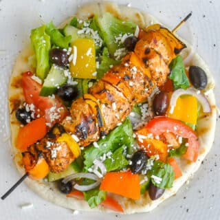 Chicken Souvlaki with Lemon Mint Tzatziki close up image with Greek Salad on a flatbread