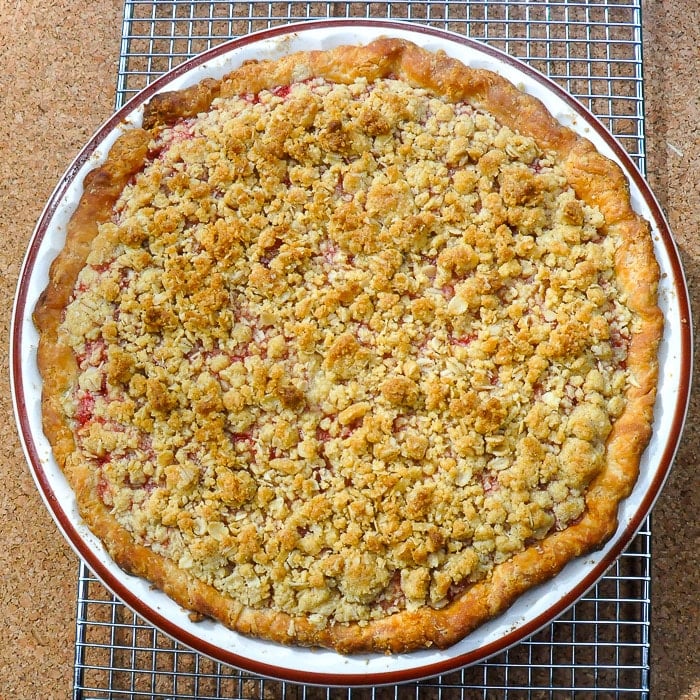 Strawberry Rhubarb Pie with Oatmeal Crumble Topping overhead photo of uncut pie cooling on a wire rack