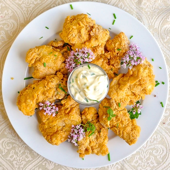 Chicken Fried Fish Nuggets on a white plate with chive flowers