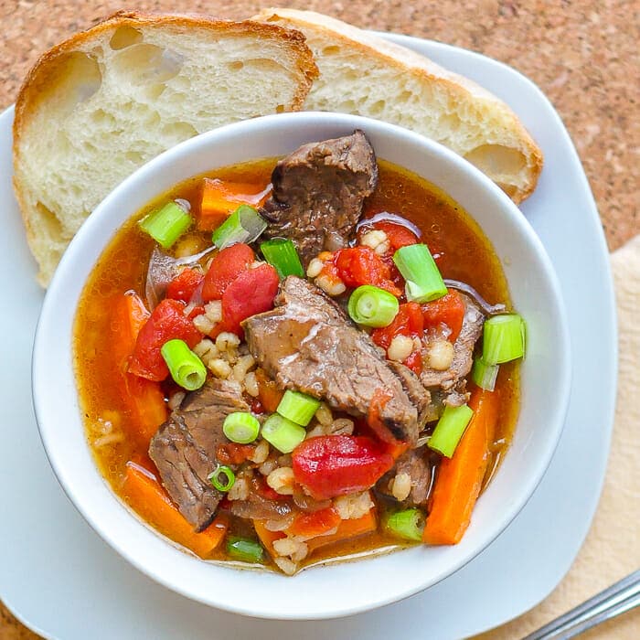 Steak Tomato and Smoked Paprika Soup shown in a white bowl with artisan bread on the side