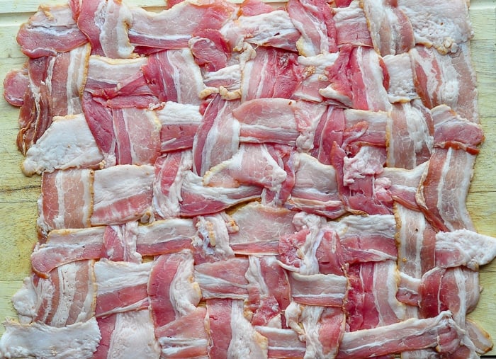 A woven bacon blanket on a wooden cutting board