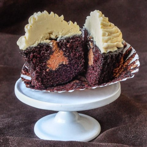 Inside Out Peanut Butter Cup Cupcakes photo of one cupcake cut open to reveal the chocolate frosting filling