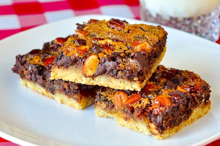 Chewy Chocolate Pecan Almond Bars stacked on a white serving plate