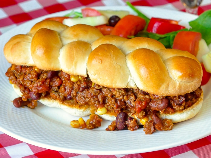 Chipotle Chili Sloppy Joes wide shot of full sandwich with salad on a white plate