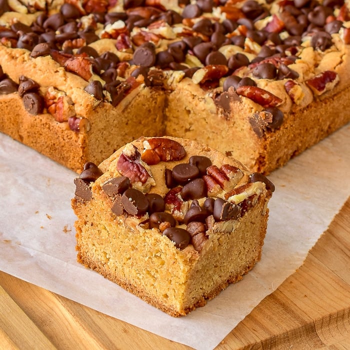 Chocolate Pecan Blondies close up of one cookie bar on a wooden cutting board