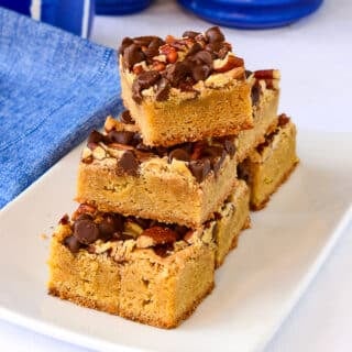 Chocolate Pecan Blondies stscked on a white serving platter