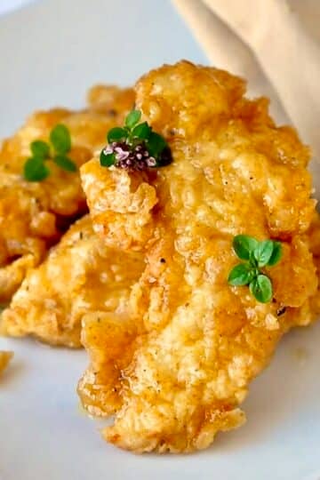 Honey Dijon Boneless Wings close up photo of wings on a white plate garnished with oregano flowers.