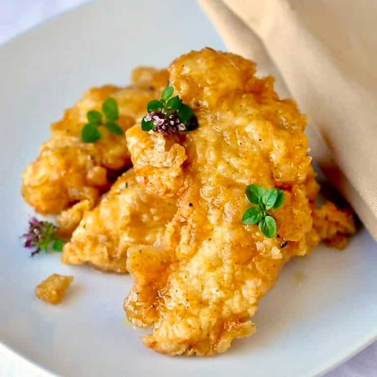 Honey Dijon Boneless Wings close up photo of wings on a white plate garnished with oregano flowers.