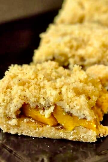 Mango Five Spice Crumble Bars close up photo in a black plate for Google featured image.