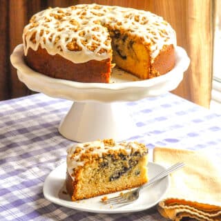 Blueberry Swirl Coffee Cake photo od entire cake on a white pedestal with one slice cut out