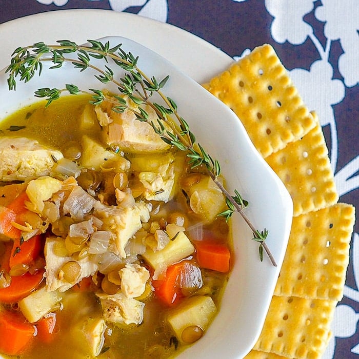 Chicken Thyme and Lentil Soup close up image of soup in a white bowl with crackers on the side