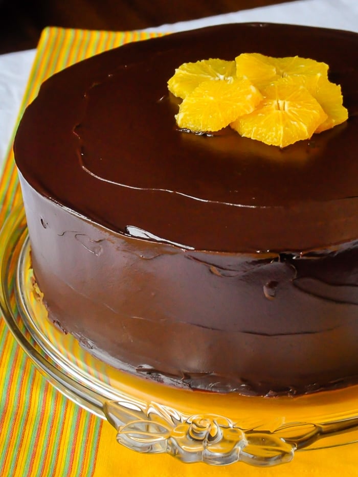 Chocolate Orange Cheesecake Layer Cake photo of uncut cake on a glass cake plate