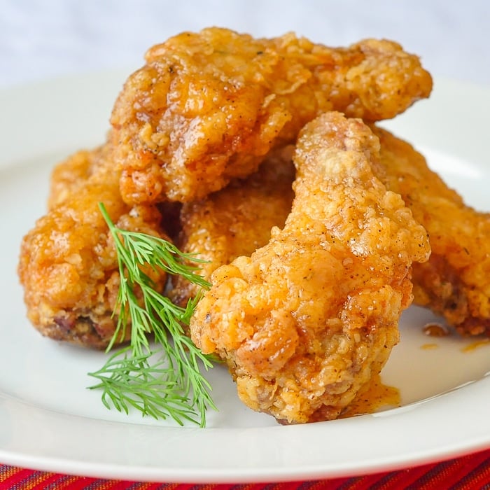 Crispy Chicken Wings with Sticky Maple Chipotle Glaze Close up photo of several wings stacked on a white plate