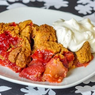 Strawberry Apple Graham Crumble close up image on a white plate with whipped cream