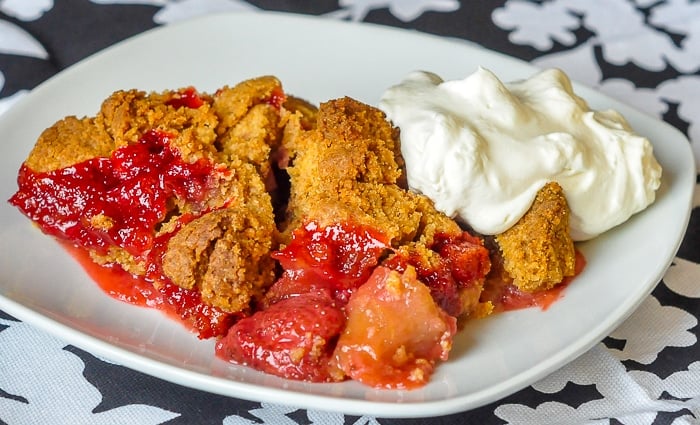 Strawberry Apple Graham Crumble wide image of full serving on a white plate with whipped cream