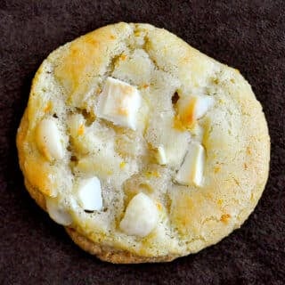White Chocolate Orange Macadamia Cookies photo of one cookie on a brown background