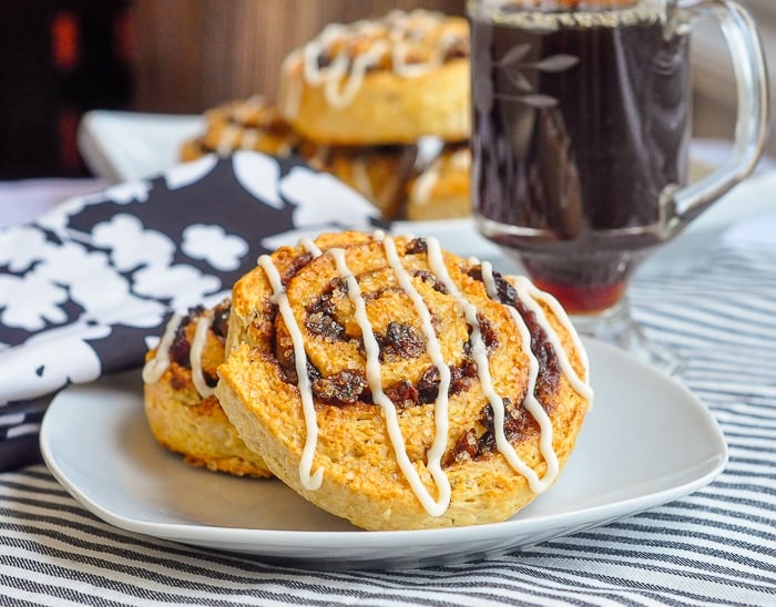 Buttermilk Biscuit Cinnamon Rolls shown on a white plate with coffee in the background