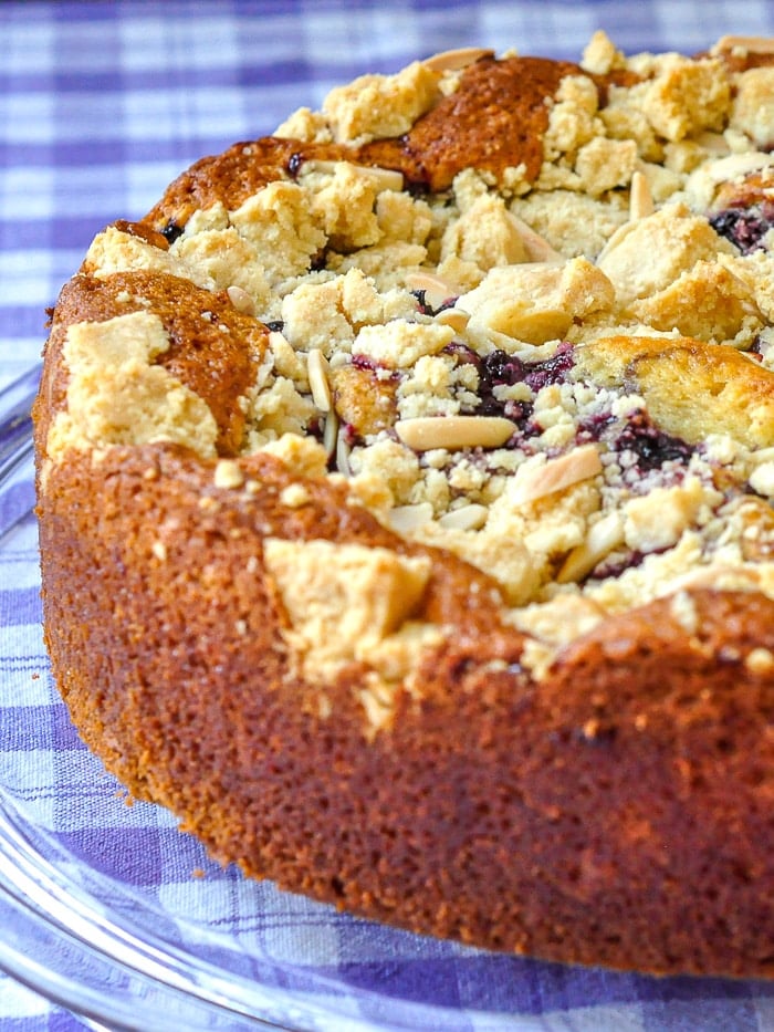 Cherry Swirl Almond Crumble Coffee Cake photo of uncut czke on a clear glass serving plate