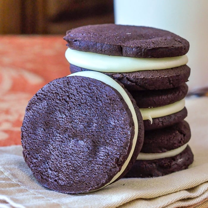 Homemade White Chocolate Fudge Oreos photo stacked on a napkin with milk in the background