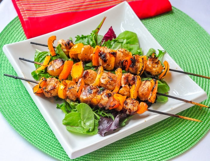 Ginger Soy Grilled Scallops on skewers on a bed of baby greens