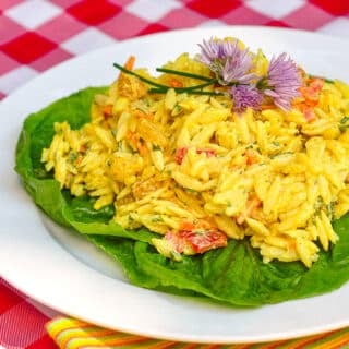 Creamy Curry Orzo Salad on a bed of lettuce on a white plate