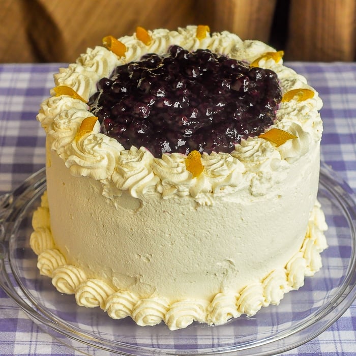Lemon Blueberry Cream Cake photo of entire uncut cake on a glass cake plate