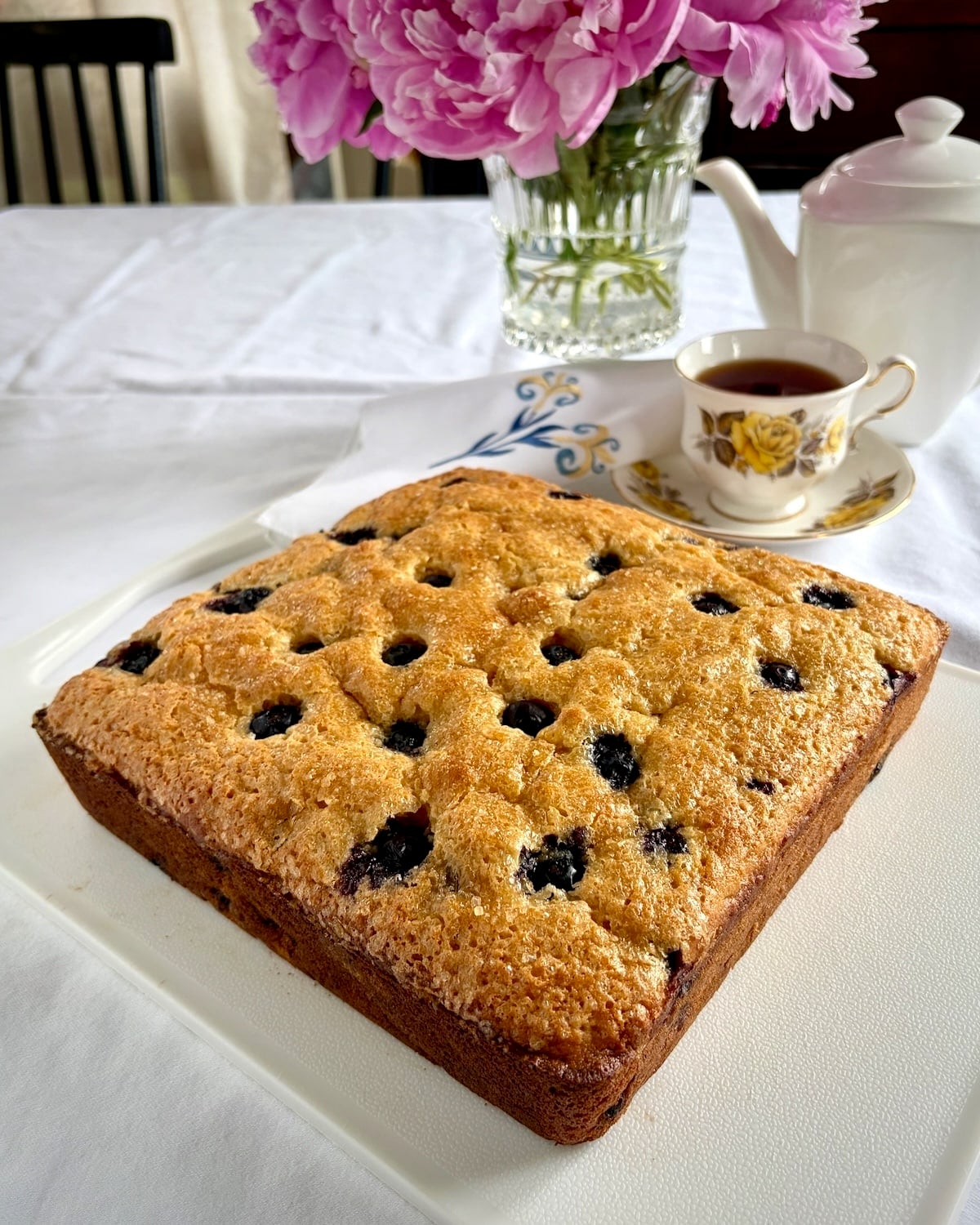 Photo of blueberry snack cake out of the pan sitting on a white cutting board