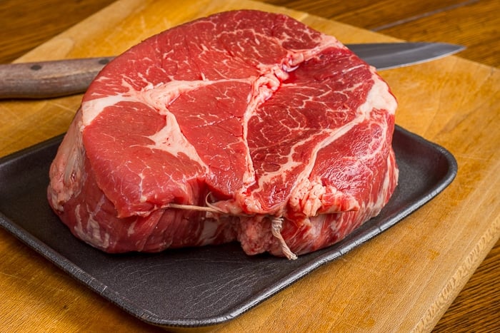 Uncooked cut of beef chuck roast on a cutting board