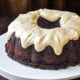 Chocolate Zucchini Cake with Cream Cheese Glaze photo of uncut cake on a white plate