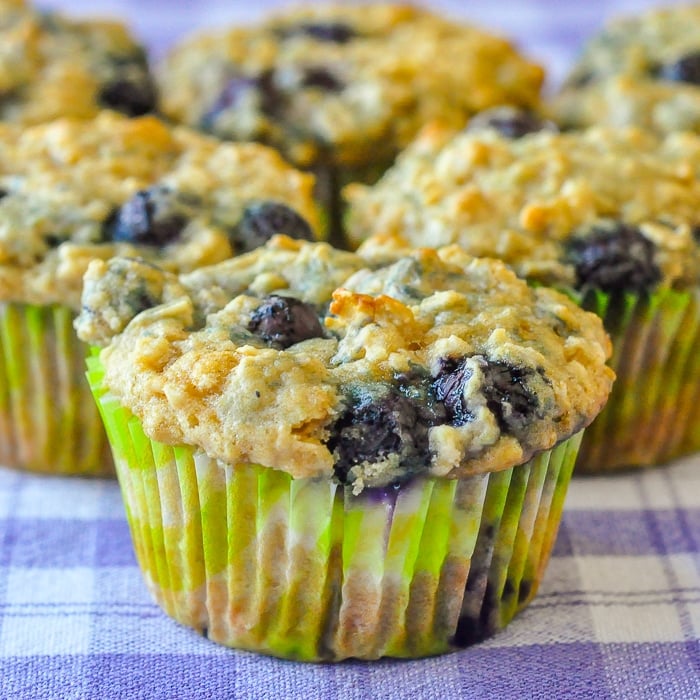 Blueberry Oatmeal Lemon Cheesecake Muffins close up shot of muffins on a blue checkered table cloth