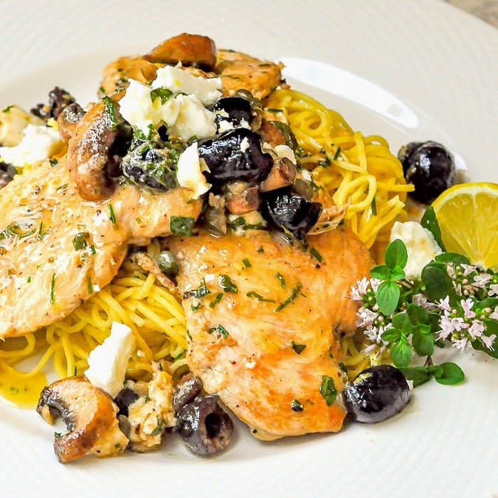 Mediterranean Lemon Butter Chicken close up photo of a single serving on a white plate