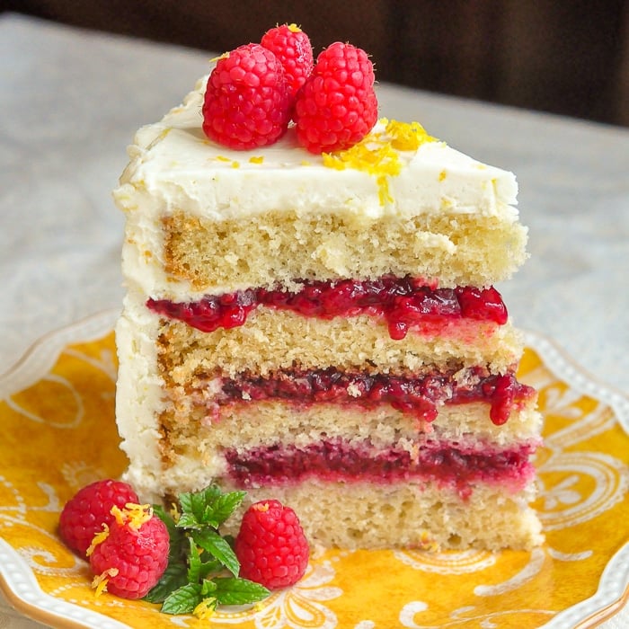 Raspberry Lemon Buttercream Cake photo of a single slice on a yellow plate showing all four layers