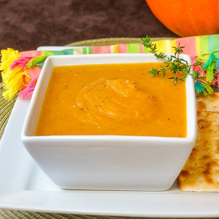 Roasted Pumpkin Soup in square white bowl with crackers on the side