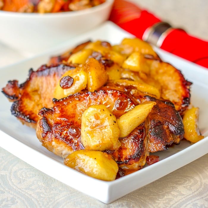 Brined Pan Seared Pork Chops with Maple Five Spice Apples shown on a white serving platter